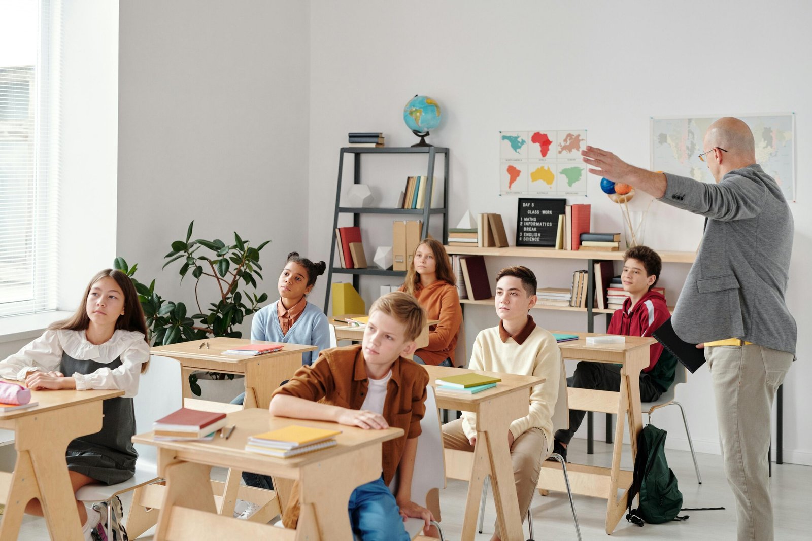 A diverse group of students attentively participating in a classroom lesson led by a teacher.