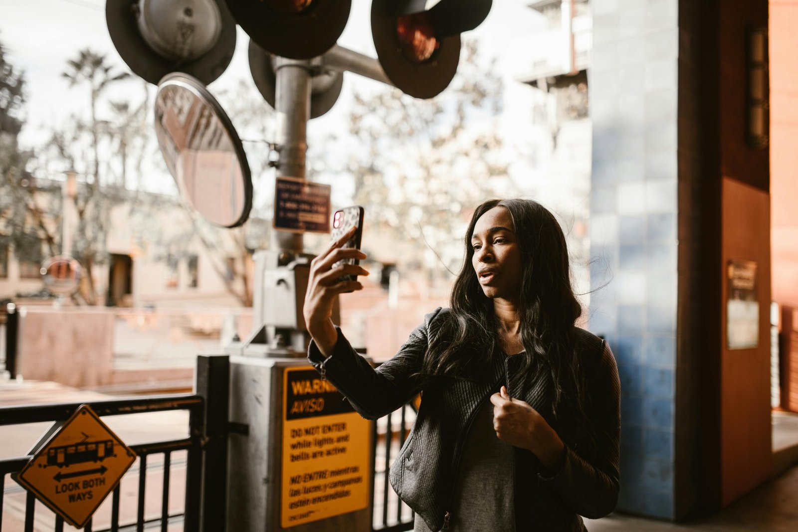 Stylish woman takes a selfie at a city crosswalk, capturing urban life.